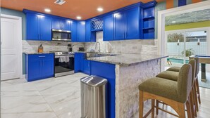 A modern kitchen with blue cabinets, a stainless steel stove, and a marble countertop. - Backyard Oasis • Pool •  Hot Tub • Putt Putt • Bar (Largo)