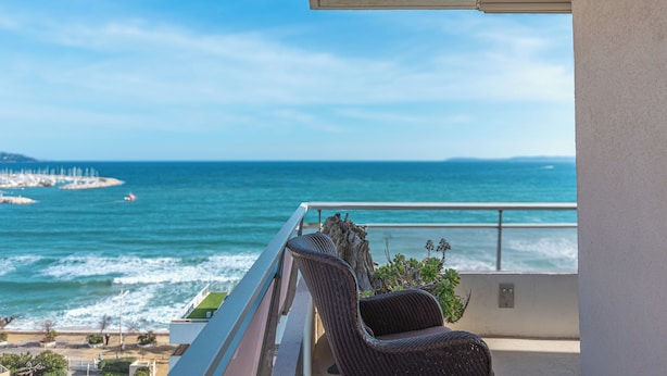 A balcony with a view of the ocean, a chair, and a plant. - Spectacular 2-Bedroom Apartment with Sea View – Market Square (LE LAVANDOU)