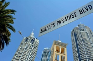 Una señal de calle que indica 'Surfers Paradise Blvd' con modernos rascacielos al fondo.