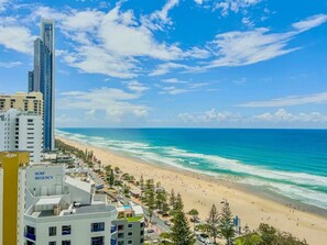 A coastal cityscape with a beach, high-rise buildings, and a Surf Regency hotel. - Luxury 2 Bedroom Ocean View Apartment in Surfers Paradise (Surfers Paradise)