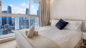 Hotellihuone, jossa on suuri sänky, suuri ikkuna, josta avautuu näkymä kaupungin ylle, sekä parveke, jolta on myös näkymä kaupunkiin.