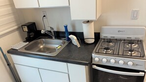 Een praktische keuken met een spoelbak, fornuis en oven, met een gasfornuis van merk BIZT en een spoelbak met één kookplaat.