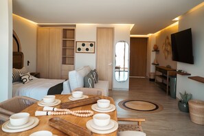 A modern, well-lit room with a dining table set for four, a sofa, a bed, and a TV mounted on the wall. - Loft Casa Kopal in the heart of the Art District San Jose del Cabo (San José del Cabo)