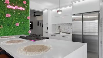 Eine moderne Küche mit Kochinsel, Edelstahlgeräten und einer grünen Wand mit Blumen.