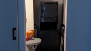 Ein Waschraum mit Waschmaschine, Trockner und einem Tisch mit Reinigungsmitteln.