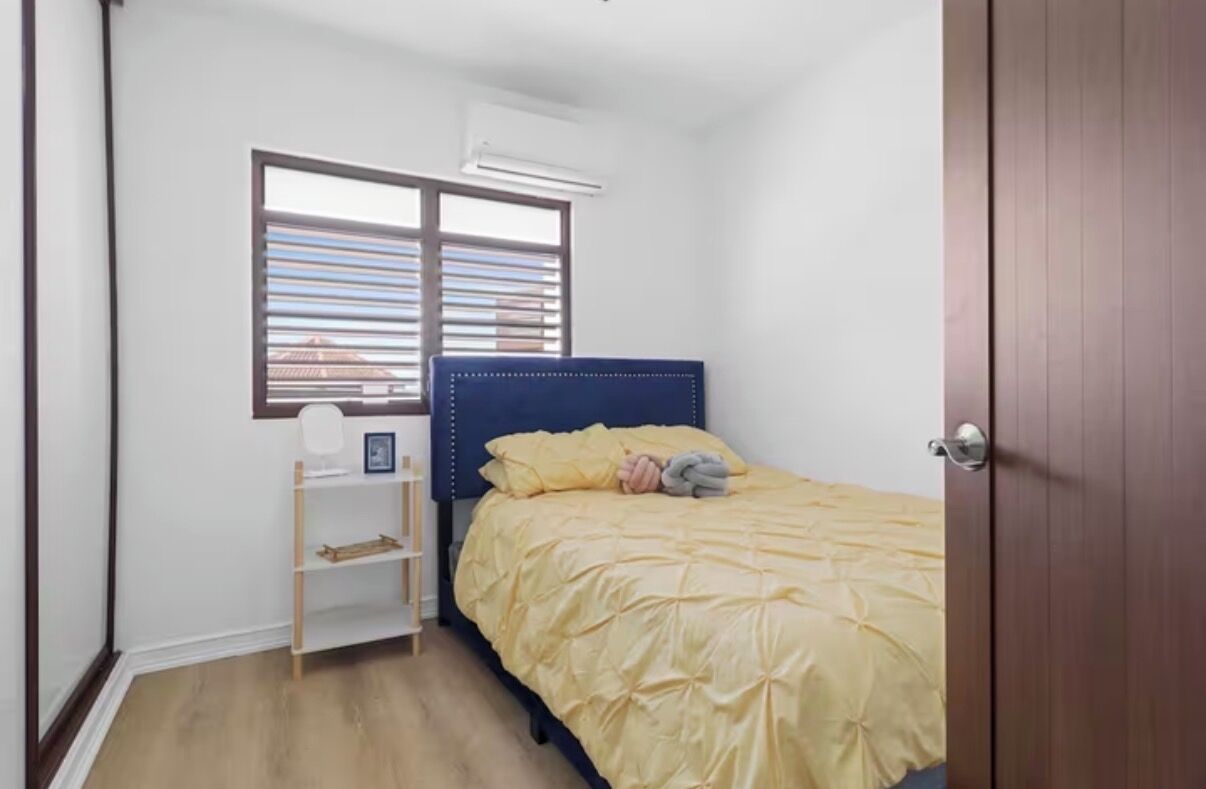 Une chambre à coucher avec un lit, une fenêtre avec des stores, une étagère et une porte.
