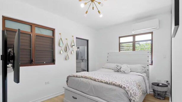 Ein Schlafzimmer mit Bett, Kleiderschrank, Spiegel und Fenster.