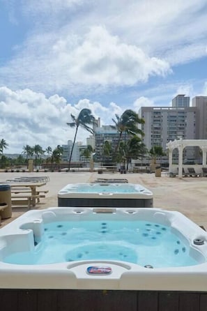 Un espace avec un jacuzzi offrant une vue sur les palmiers et les bâtiments en arrière-plan.