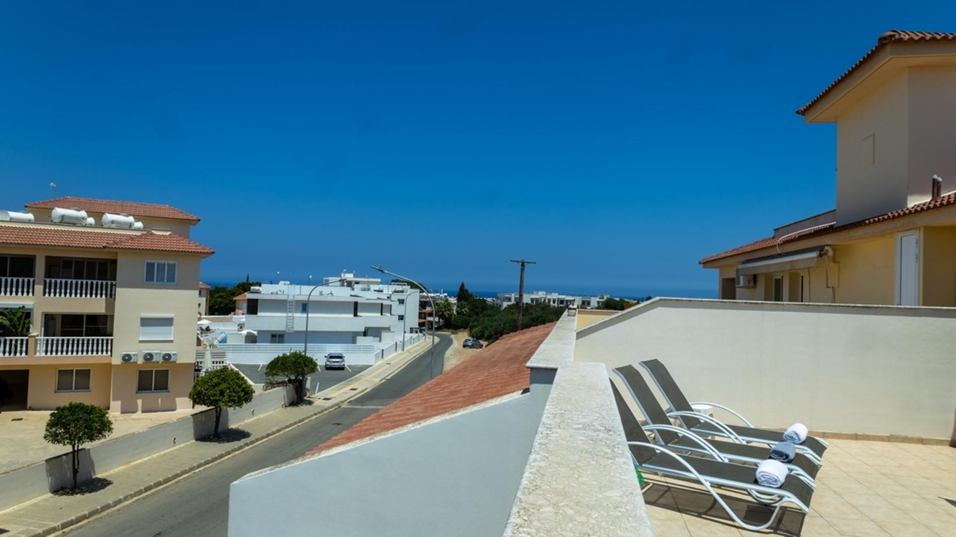 Zona residencial con vista despejada al mar, una calle pavimentada y un edificio con balcón.
