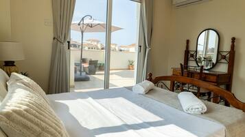A hotel room with a bed, a wooden dresser, a mirror, and a view of the outdoor area.