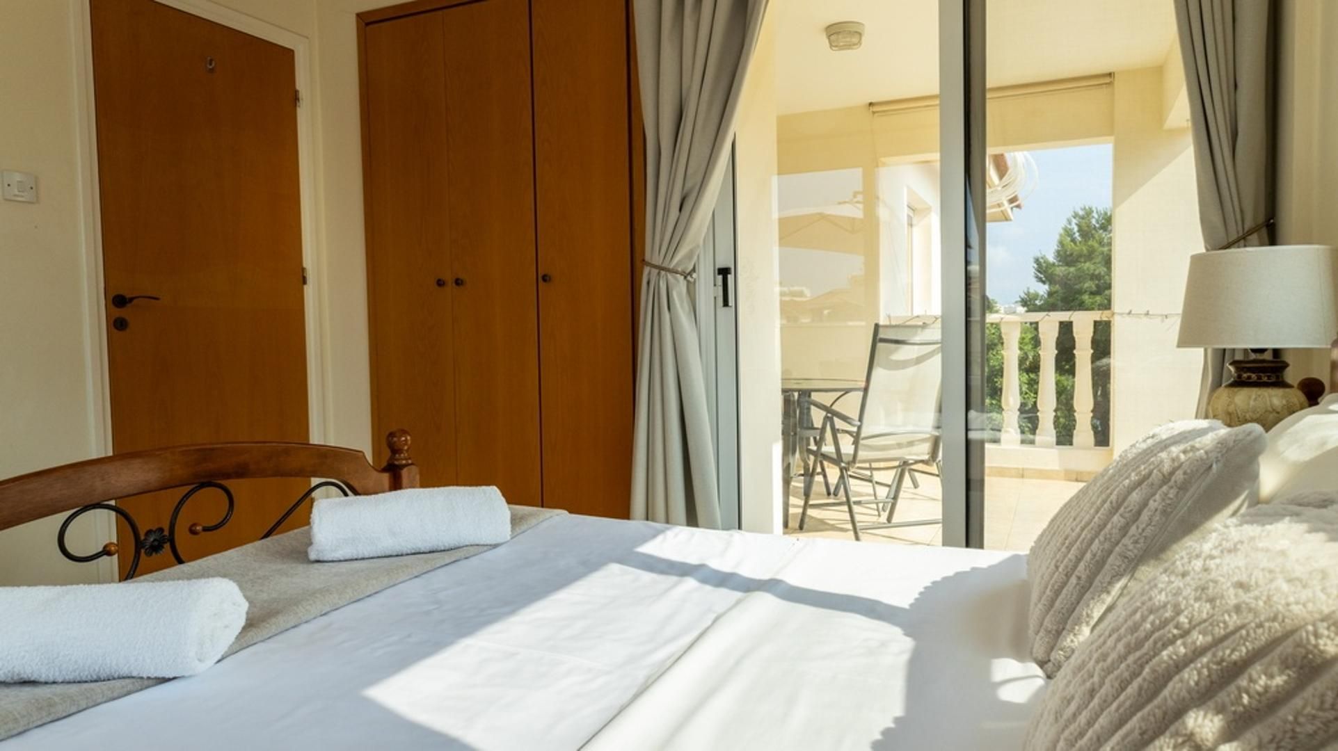 Habitación de hotel con una cama, una silla, una mesa y un balcón con vistas.