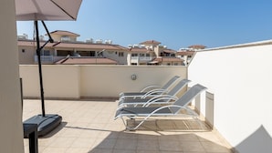 A rooftop terrace with lounge chairs, a table, and a ceiling fan. - Penthouse Apartment Sleeps 4 - Sea Views, Pool (Kapparis)