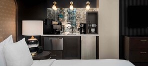 A compact hotel room with a kitchenette, a bed, a bedside table with a lamp, and a TV. - Studio Room for the Super Bowl! (San Francisco)