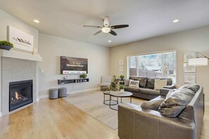 Un salon moderne doté d’une cheminée, d’un ventilateur de plafond, d’un téléviseur à écran plat, d’un canapé et d’une table basse.
