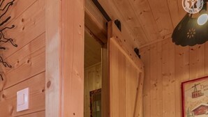 A wooden cabin interior with a wooden staircase leading to a lower level, a ceiling light fixture, and a framed picture on the wall. - ô LIMPâR - HAUTELUCE - Gîte (HAUTELUCE LES SAISIES)