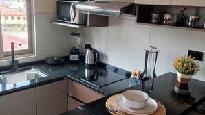 A modern kitchen with a black countertop, a built-in microwave, a coffee maker, and a blender. - Modern studio apartment in downtown area of the city (Cochabamba)