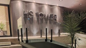 A modern hotel lobby with a vertical wooden panel design, a central pool, and a palm tree. - Modern studio apartment in downtown area of the city (Cochabamba)