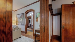 Un salon spacieux doté d’un parquet, d’un canapé beige et d’un tapis blanc. On y trouve une porte en bois et un tableau encadré accroché au mur.