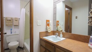 A bathroom with a toilet, sink, and shower. There are towels hanging on the wall and a mirror above the sink. - Adorable 1-bedroom condo - 201 Lava Hot Springs Resort (Lava Hot Springs)