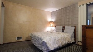 A hotel room with a bed, a wall-mounted light, and a vent on the wall. - Adorable 1-bedroom condo - 201 Lava Hot Springs Resort (Lava Hot Springs)