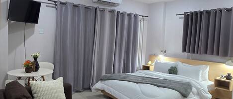 Una habitación de hotel moderna con cama, sofá, televisor y aire acondicionado.