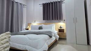A modern bedroom with a bed, bedside tables, a wardrobe, and an air conditioning unit.