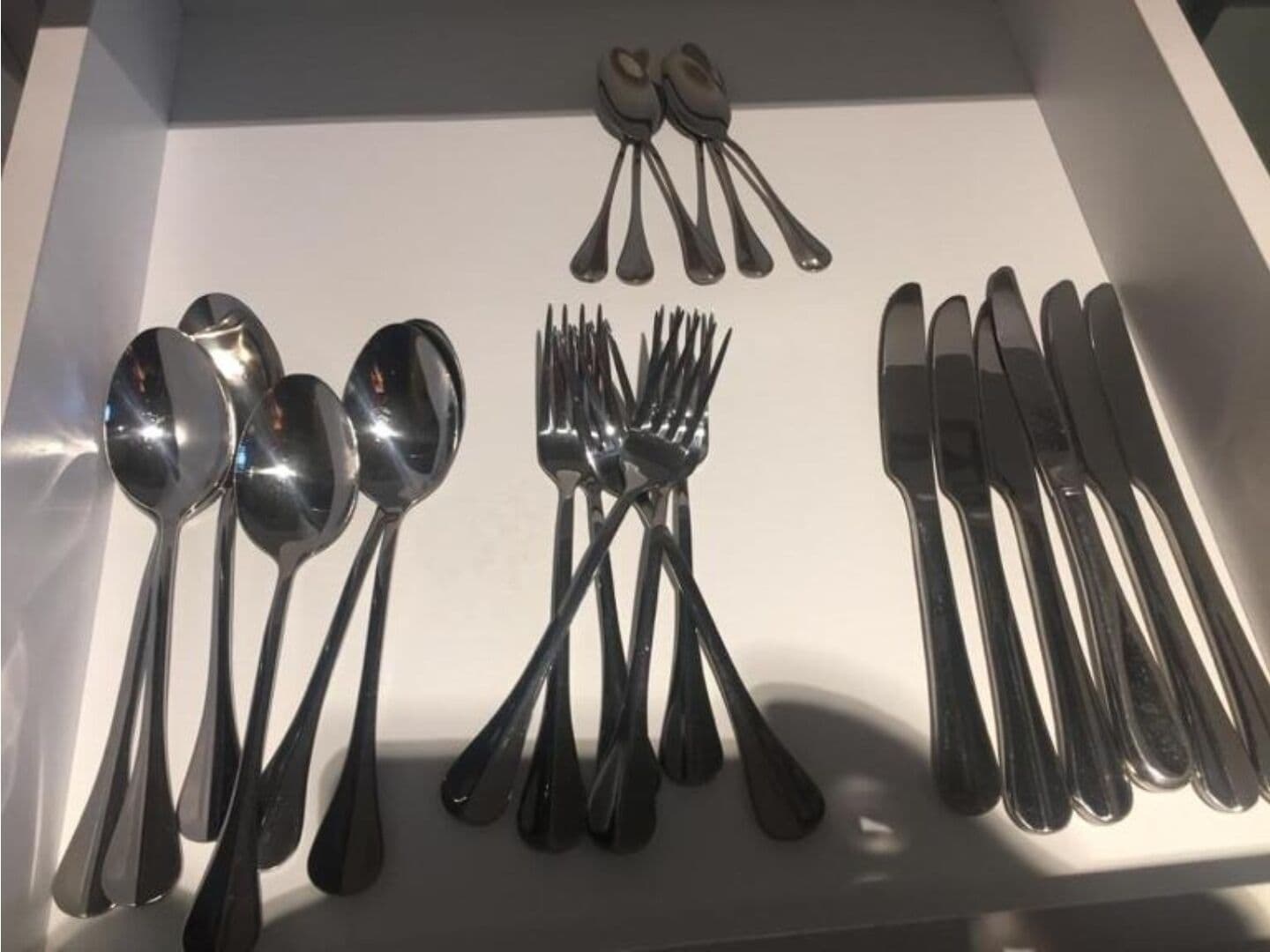 A drawer containing various silverware including spoons, forks, and knives.