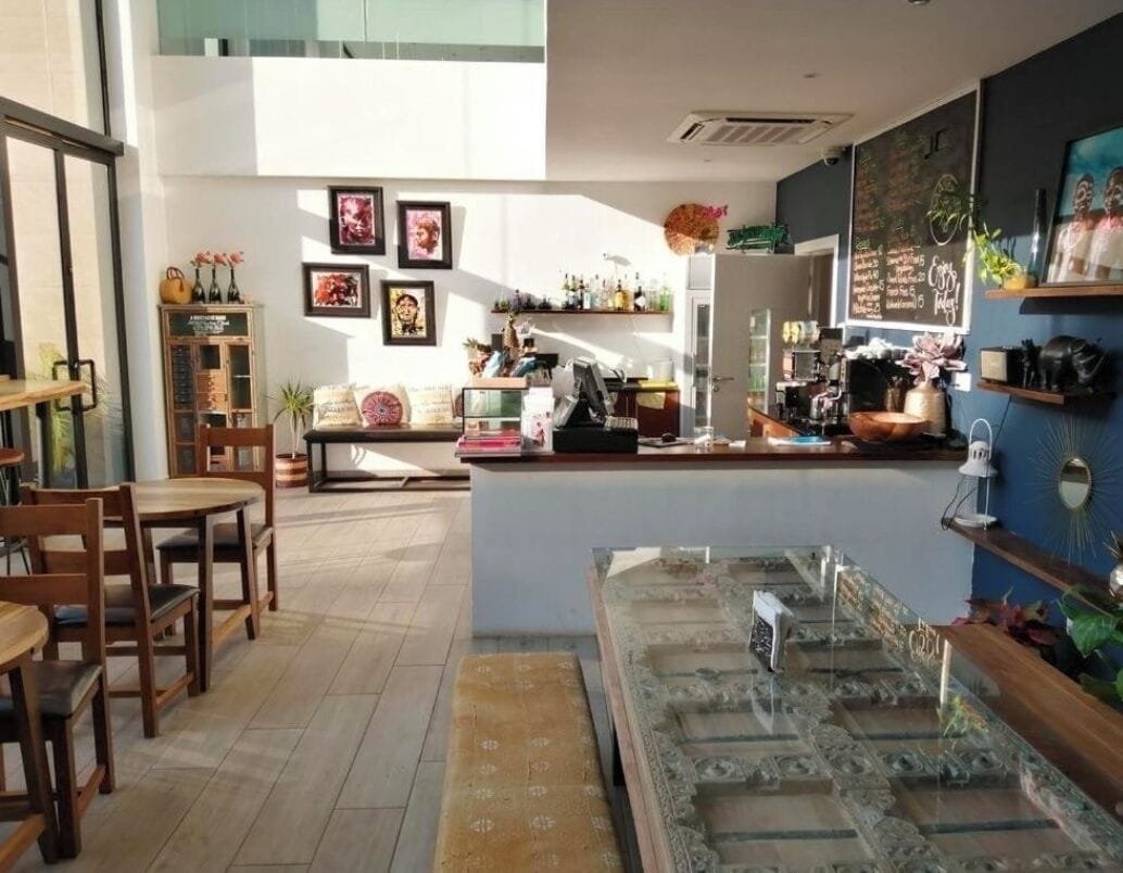 Una cafetería con muebles de madera, una barra con una máquina de café y varias decoraciones en las paredes.