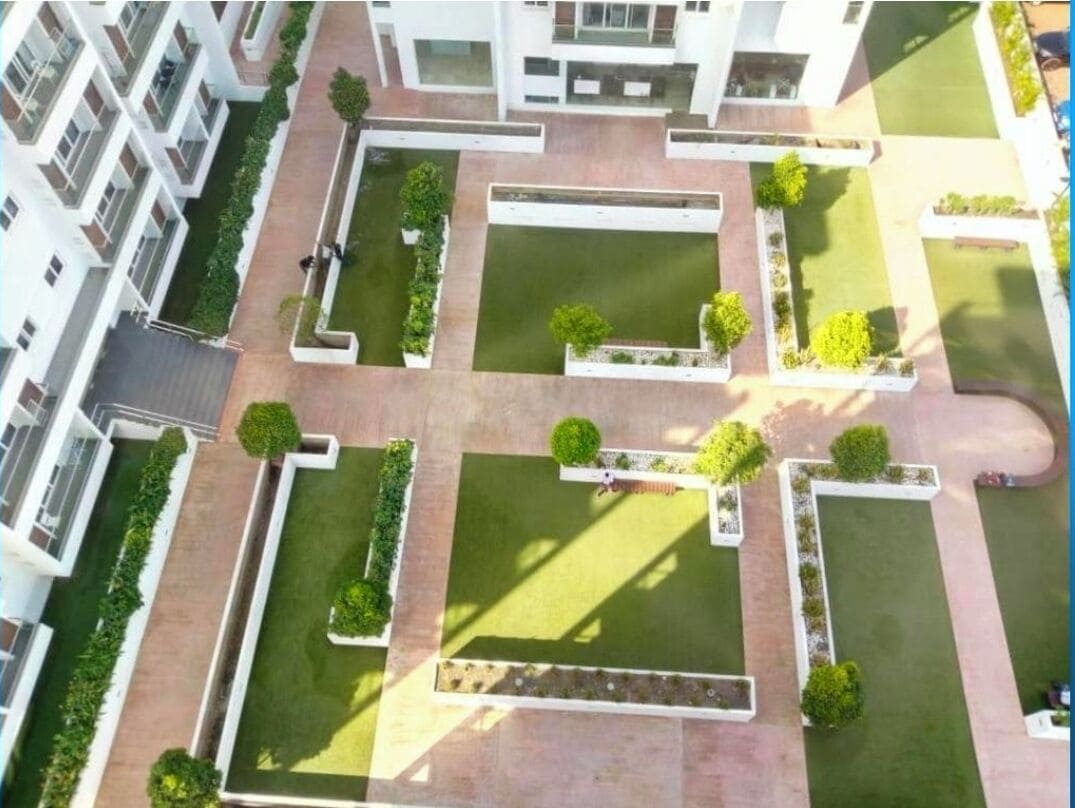 Vista aérea de un complejo residencial con varios edificios, césped verde y senderos.