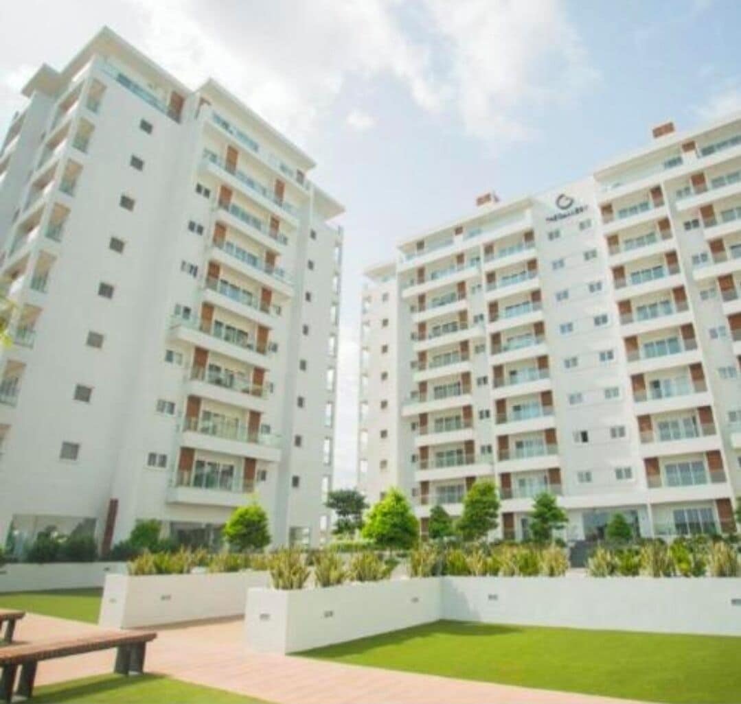 Un moderno edificio de apartamentos con varios pisos, balcones y un césped bien cuidado.
