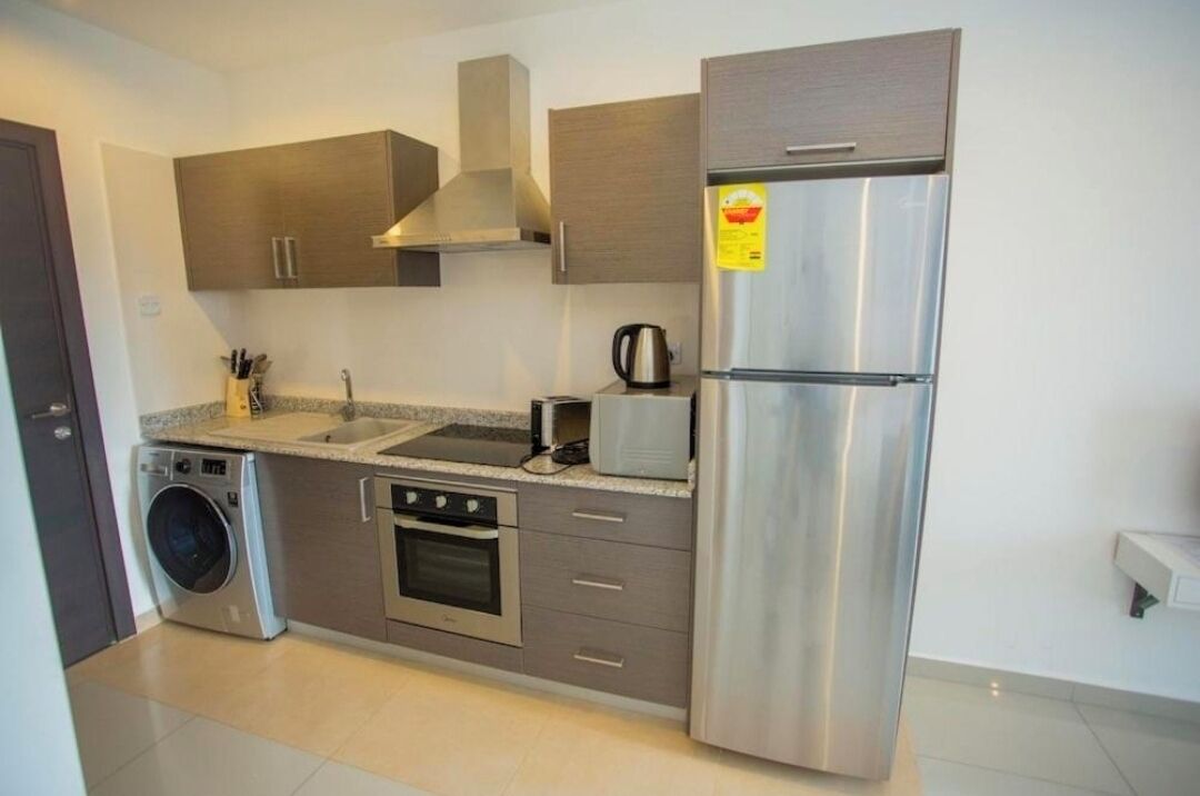 Una cocina moderna con electrodomésticos de acero inoxidable, horno empotrado, lavadora y cafetera.