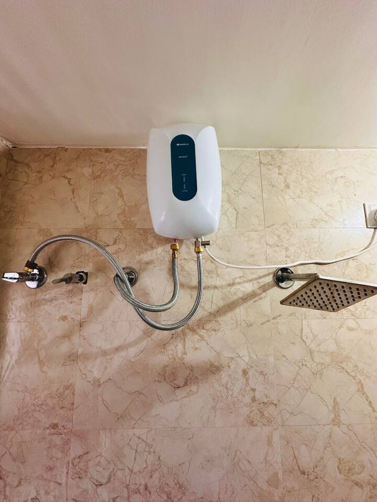 Un baño con ducha empotrada, cabezal de ducha de mano y panel de control.