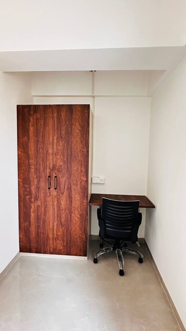 Ein Zimmer mit Holzschrank, Schreibtisch und Stuhl sowie einer weißen Wand.