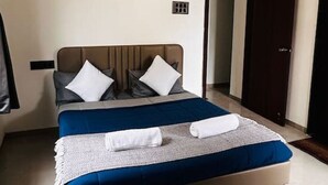 A modern bedroom with a bed, pillows, and a ceiling fan. - Seagull Nest: AC 2BHK Apartment by Bleisure (Pimpri-Chinchwad)