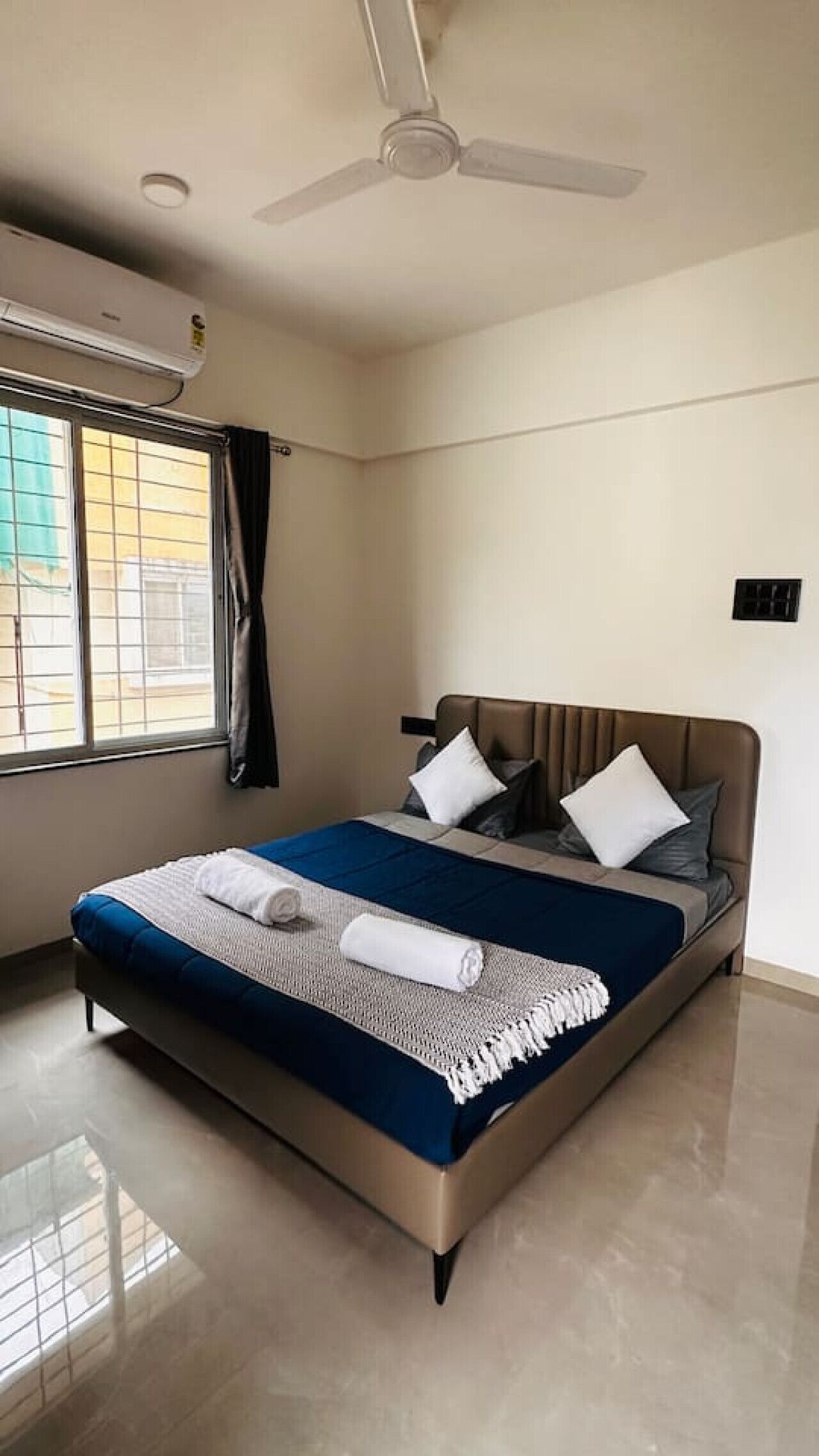 A modern bedroom with a bed, pillows, a ceiling fan, and an air conditioning unit.