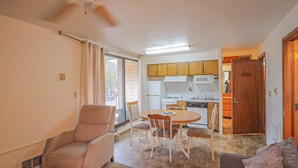 Un espacio habitable compacto con comedor, kitchenette y una silla cerca de la ventana.