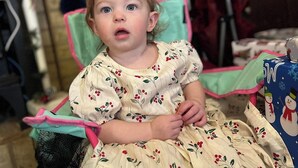 A child sitting in a chair with a floral dress, a wooden wall, and a coat rack in the background. - Enjoy a delightful campground experience in charming LaGrange (LaGrange)