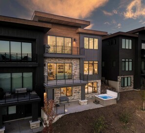 Ein modernes Mehrfamilienhaus mit Balkon, Whirlpool und einer Fassade aus Stein.