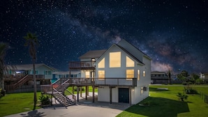 A two-story house with a balcony, a garage, and a well-maintained lawn. - Cozy Coastal Home, Minutes from the Beach (Jamaica Beach)