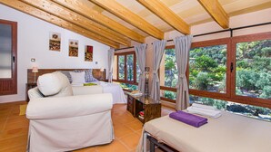 Une pièce avec un lit, un canapé et une fenêtre donnant sur un paysage verdoyant.