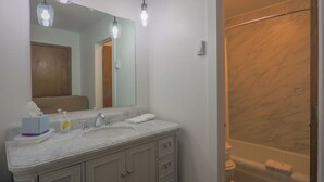 A bathroom with a marble sink, two faucets, a mirror, and a shower with a marble wall. - Quaint 1-bedroom condo is perfect for relaxing 101 - Lava Hot Springs Resort (Lava Hot Springs)