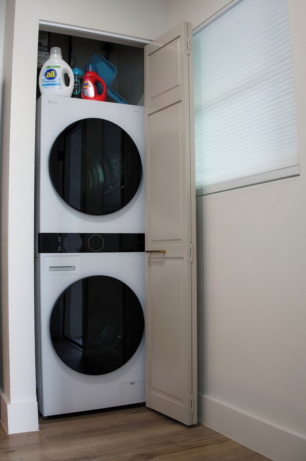 Pequeña lavandería blanca con dos puertas, que incluye lavadora y secadora integradas.