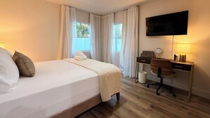 Ein Hotelzimmer mit Bett, Schreibtisch, Stuhl, Fernseher und Vorhängen.