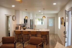 Una cocina moderna con una isla central, taburetes de bar e iluminación colgante.