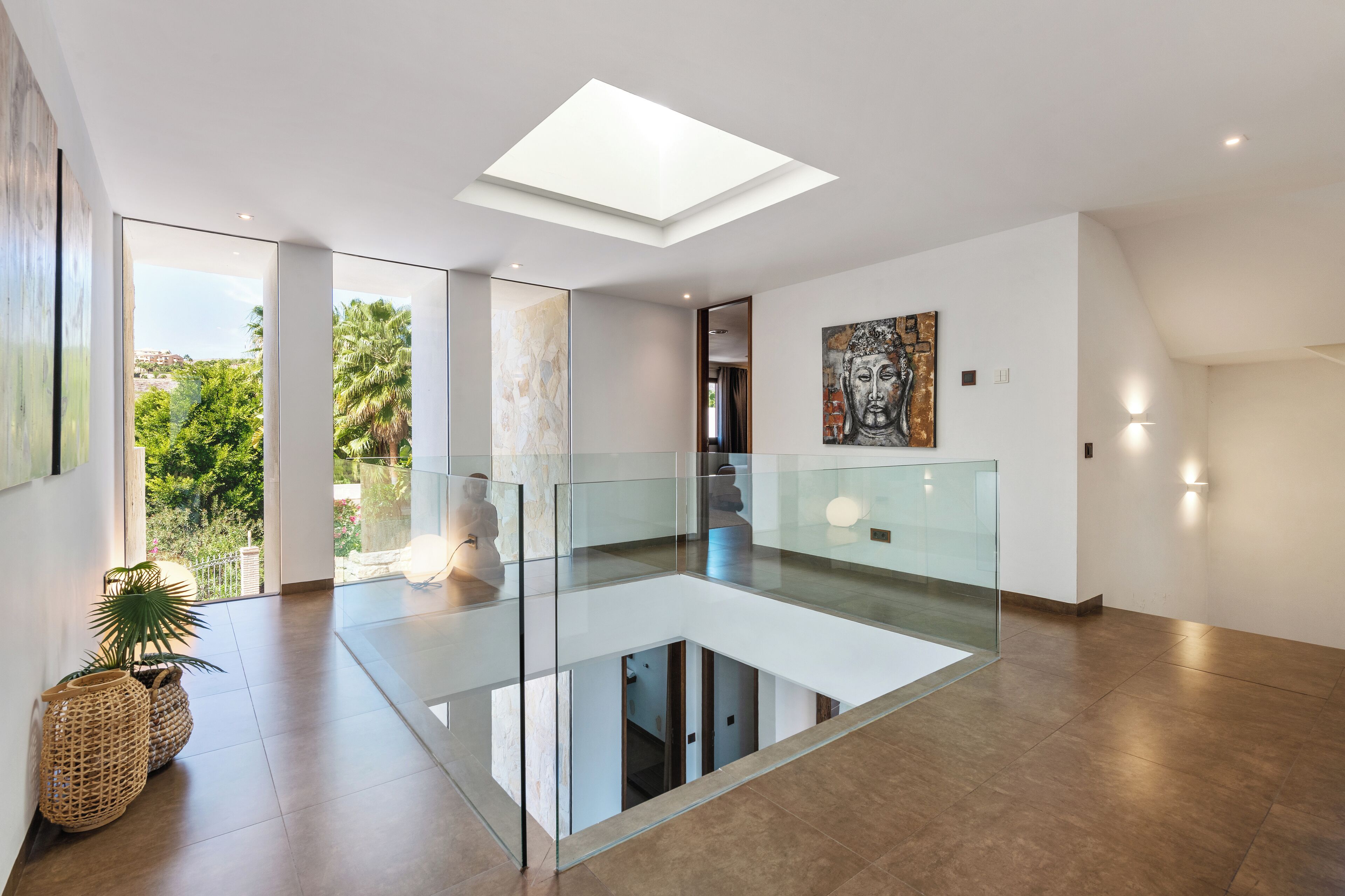 A spacious interior with a glass floor, a skylight, and a view of greenery outside.