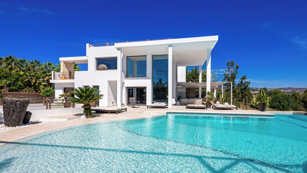 A modern house with a swimming pool, large windows, and a balcony.