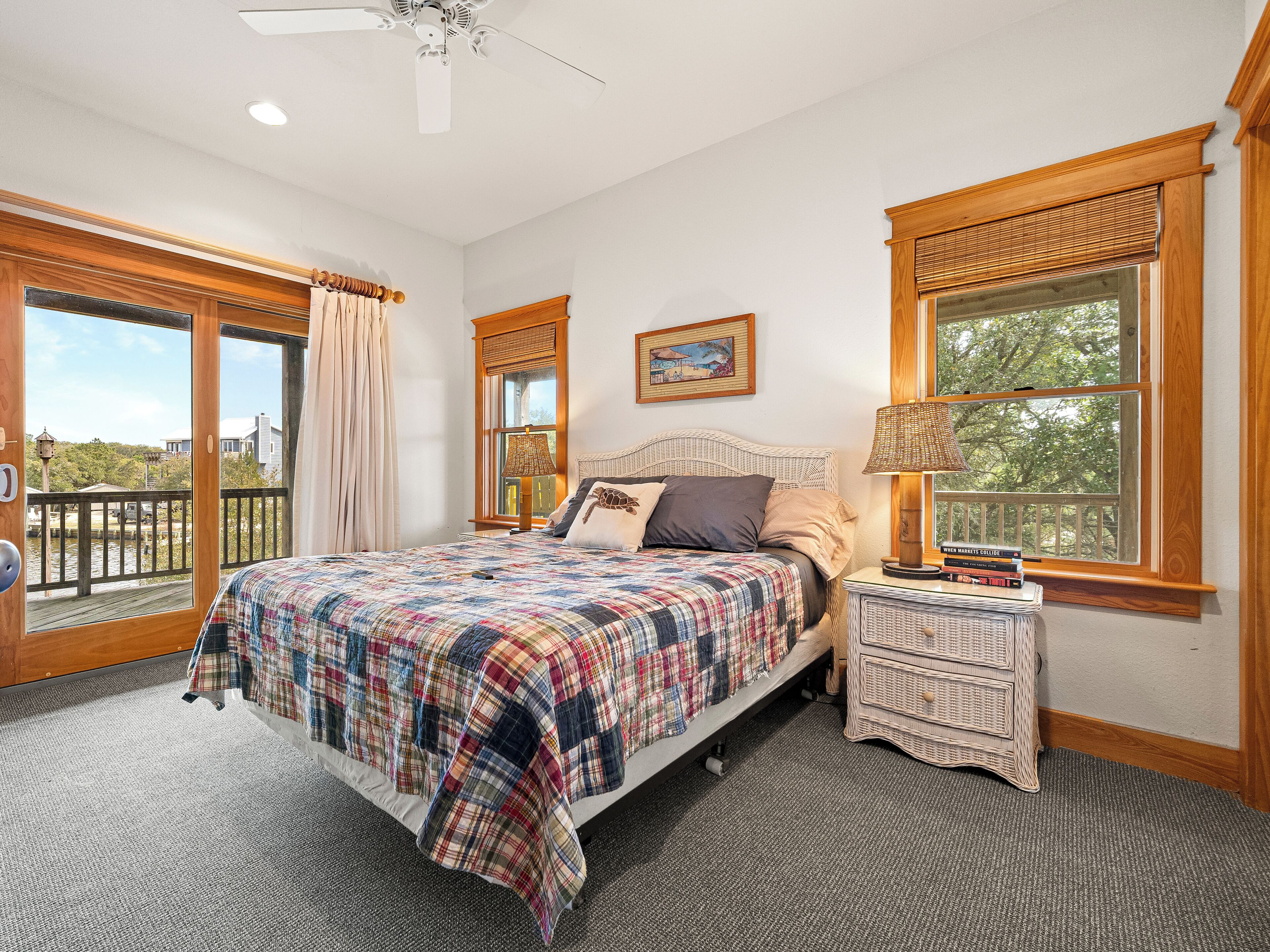 Une chambre à coucher avec un grand lit, une table de chevet, une fenêtre donnant sur un beau paysage et un ventilateur de plafond.
