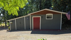 Un edificio de una planta con una puerta roja, una ventana pequeña y una bandera estadounidense.