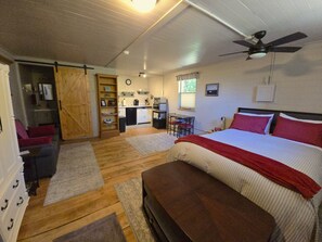 A bedroom with a bed, a desk, a chair, a wardrobe, and a ceiling fan. - Charming cottage in Kingston perfect for a relaxing getaway. (Kingston)