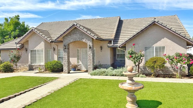 A two-story house with a stone archway entrance, a stone facade, and a well-maintained lawn. - Full 3-Bdrm home, EV charger & space to park anything.  (Madera)